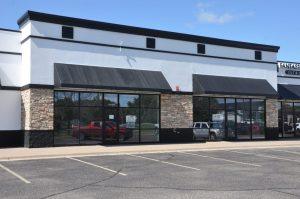 A white and black building with black awnings and square windows.